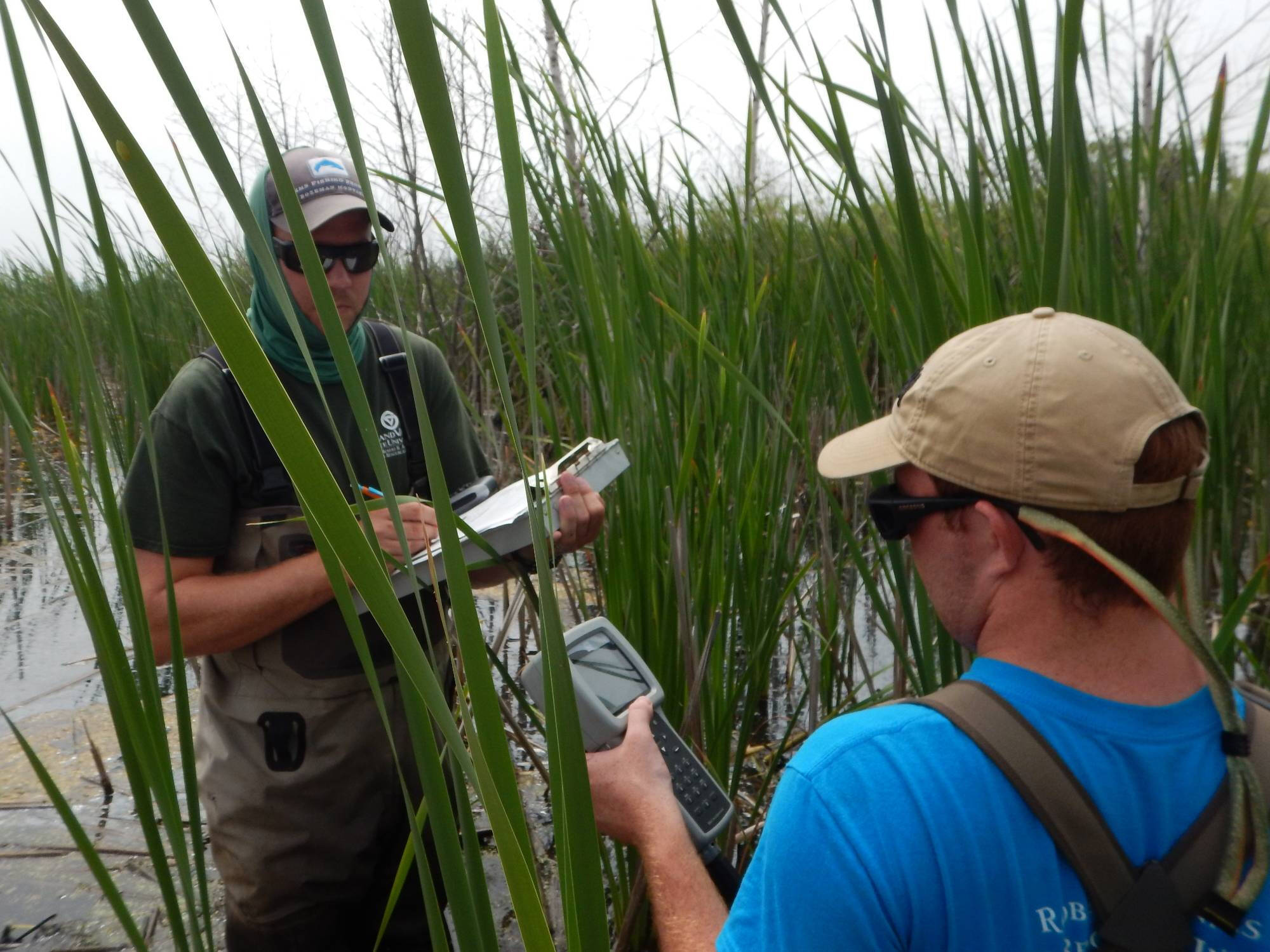 Travis and Alan record data from the water quality sonde on a clipboard.